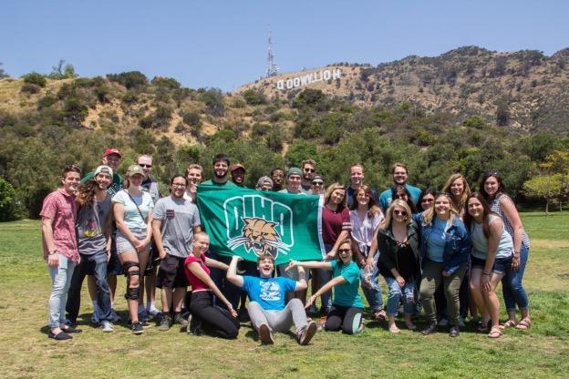 Ohio University students pose with an OHIO flag in front of the Hollywood sign